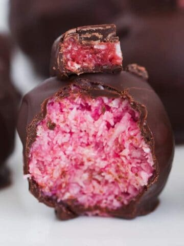 A half-eaten Cherry Ripe Ball covered in dark chocolate.