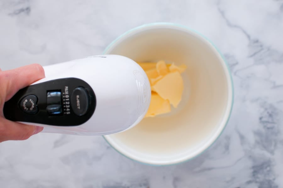 Hand-held electric beaters mixing butter in a bowl. 