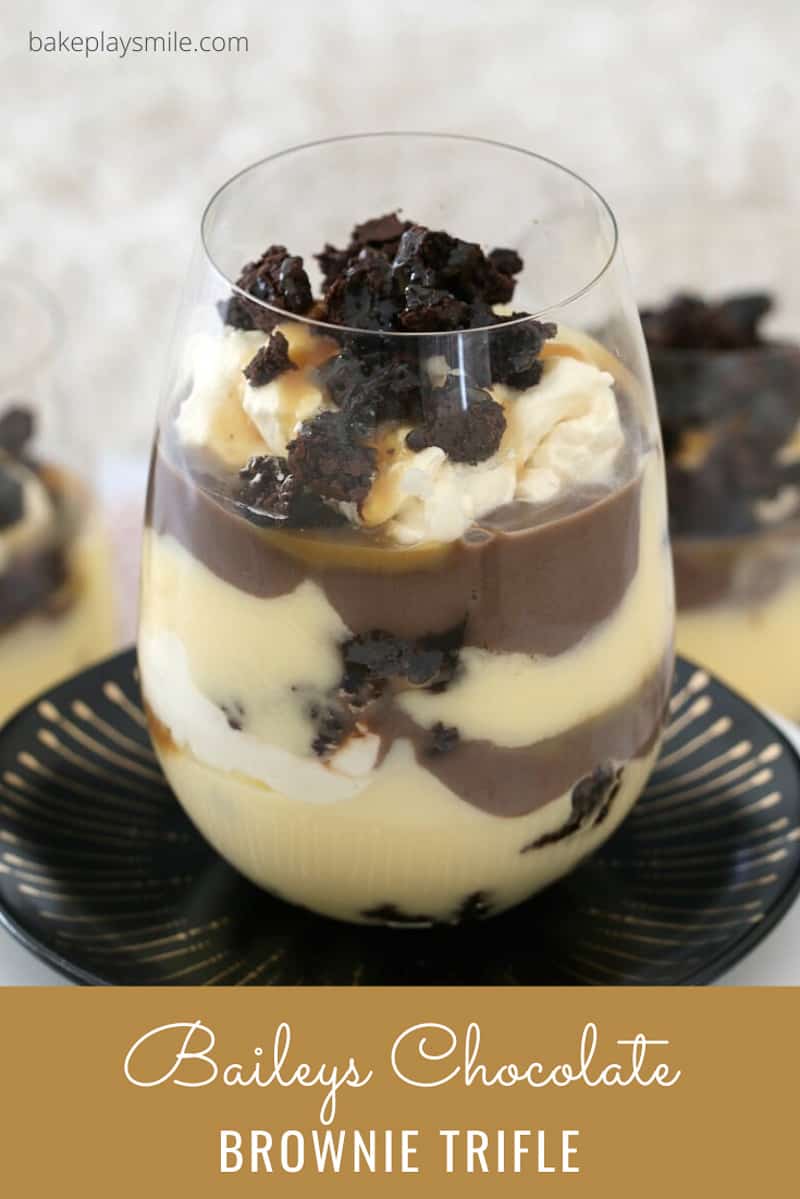A stemless wine glass filled with Baileys, custard, brownies, cream and salted caramel layered in a trifle.