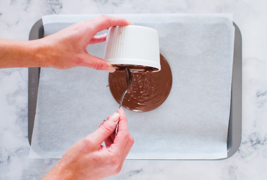 Melted milk chocolate being poured onto a baking paper lined tray.