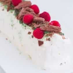 A whipped cream chocolate ripple cake decorated with raspberries, Peppermint Crisp and chocolate.