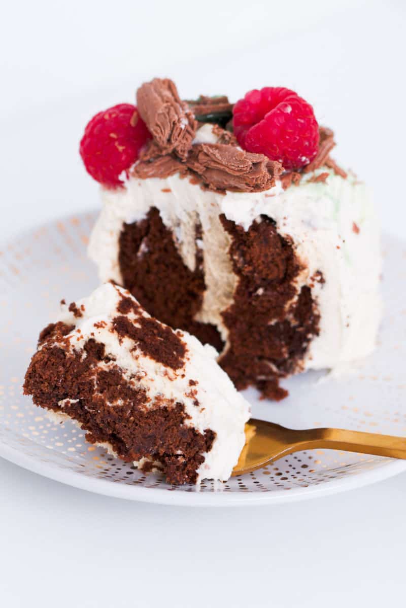 Soft choc ripple cake on a fork with whipped cream, raspberries and chocolates.