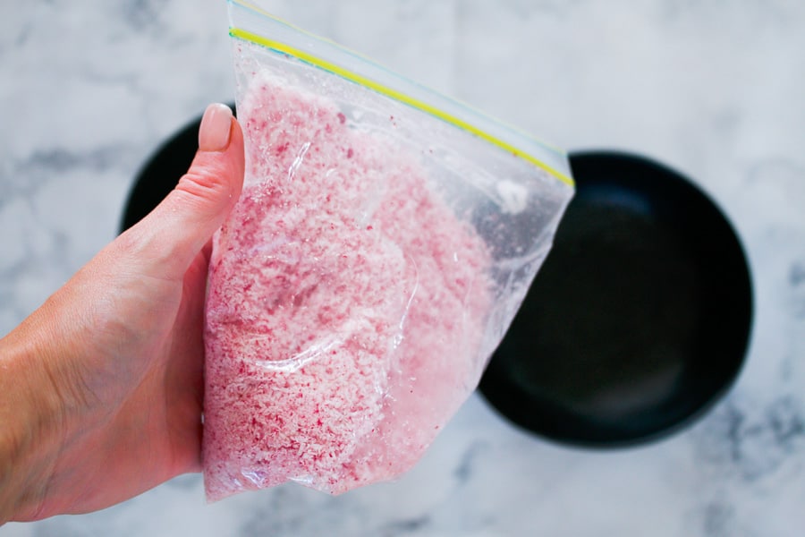 Coconut being shaken in a plastic bag with red food colouring.