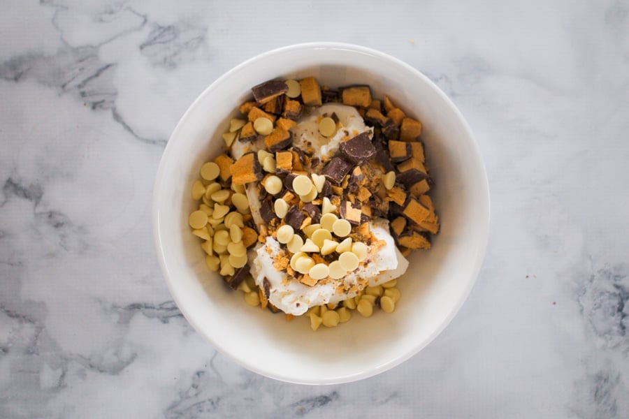Vanilla ice-cream in a bowl with chopped honeycomb and chocolate chips. 