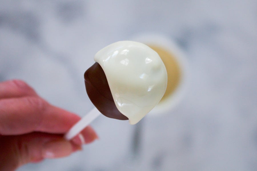 White chocolate being drizzled over a chocolate coated marshmallow.