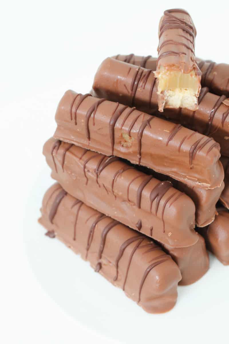 A pile of homemade chocolate bars with a half-eaten caramel bar on top.