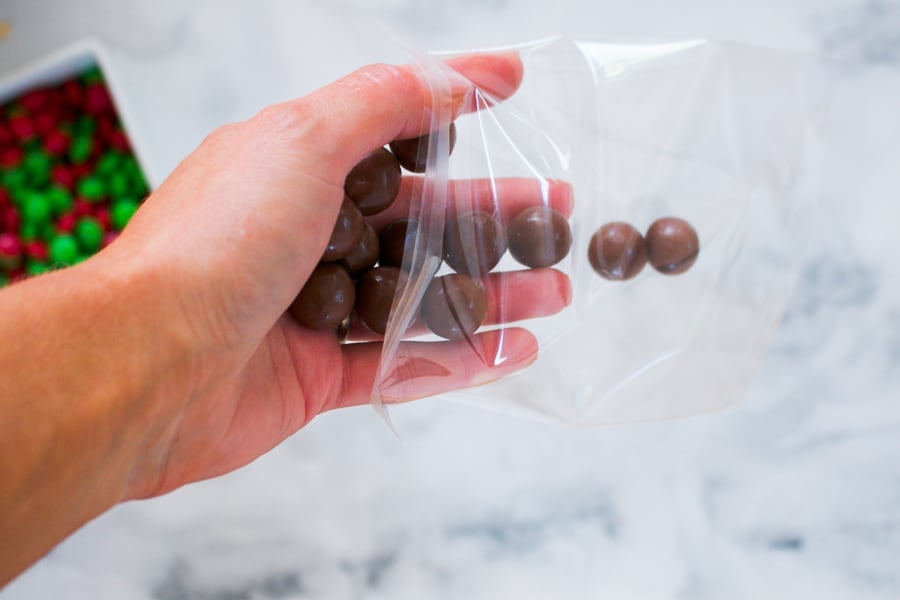 Maltesers being poured into a clear plastic bag.