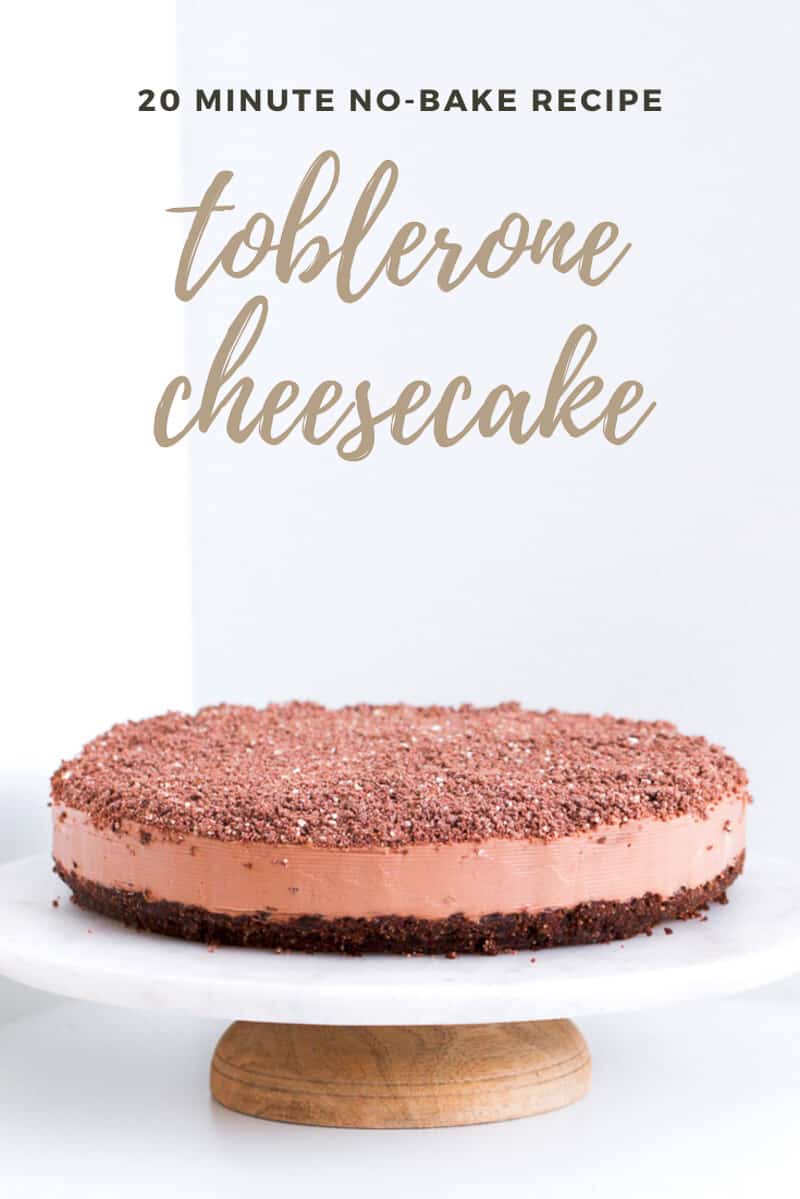 A chocolate Toblerone cheesecake topped with grated chocolate on a white cake stand.