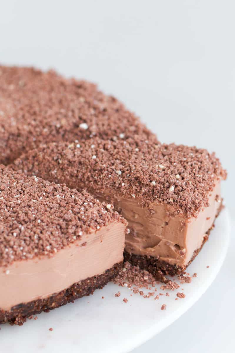 A Toblerone chocolate cheesecake topped with grated chocolate, with one slice partly removed.