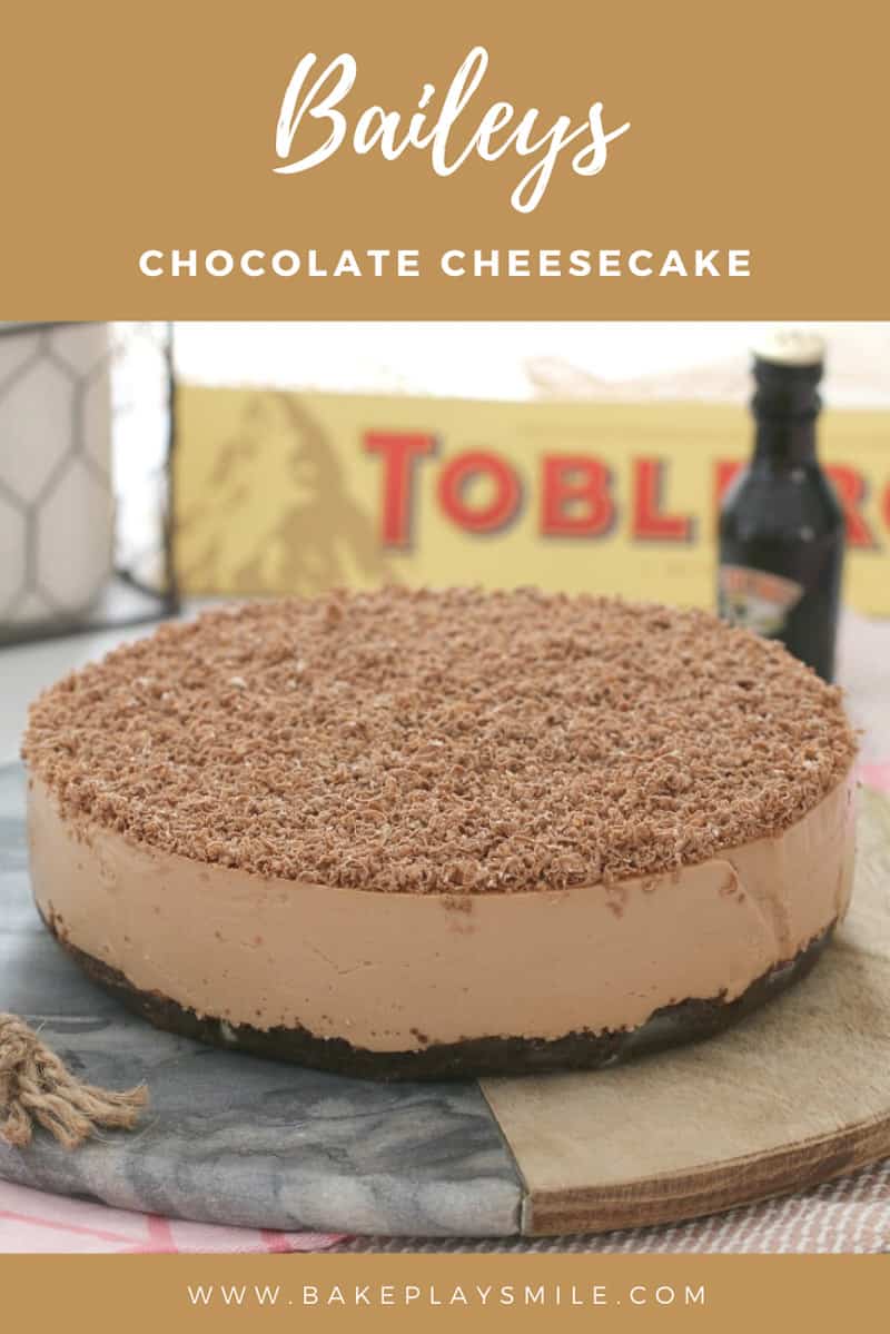 A chocolate cheesecake decorated with grated chocolate, with Toblerone and Baileys in the background.