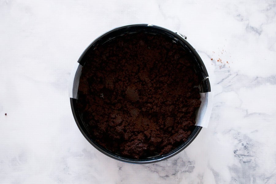 Chocolate biscuit crumbs and melted butter pressed into a round tin as the base of a cheesecake.