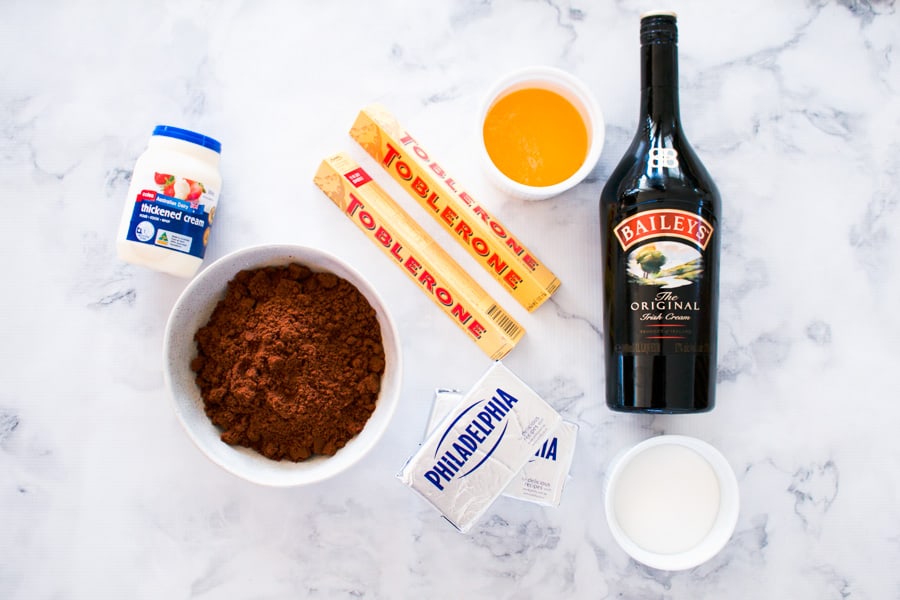All the ingredients for a chocolate Baileys cheesecake placed on a marble bench