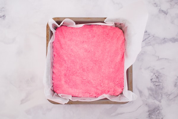 Pink coconut slice in a baking tin.