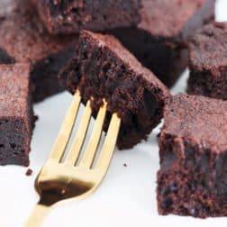 Rich and dense chocolate brownies on a gold fork.