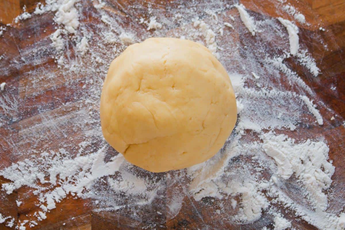 A ball of sweet pie pastry on a floured chopping board.