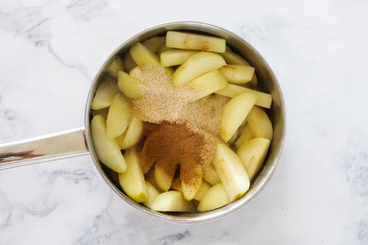 Sliced apple, sugar and cinnamon in a saucepan.