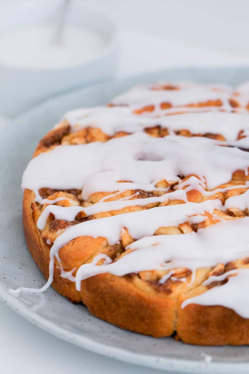 A plate of apple cinnamon rolls with white sugar glaze over the top.