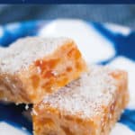 Pieces of apricot and coconut no-bake slice on a blue and white plate.