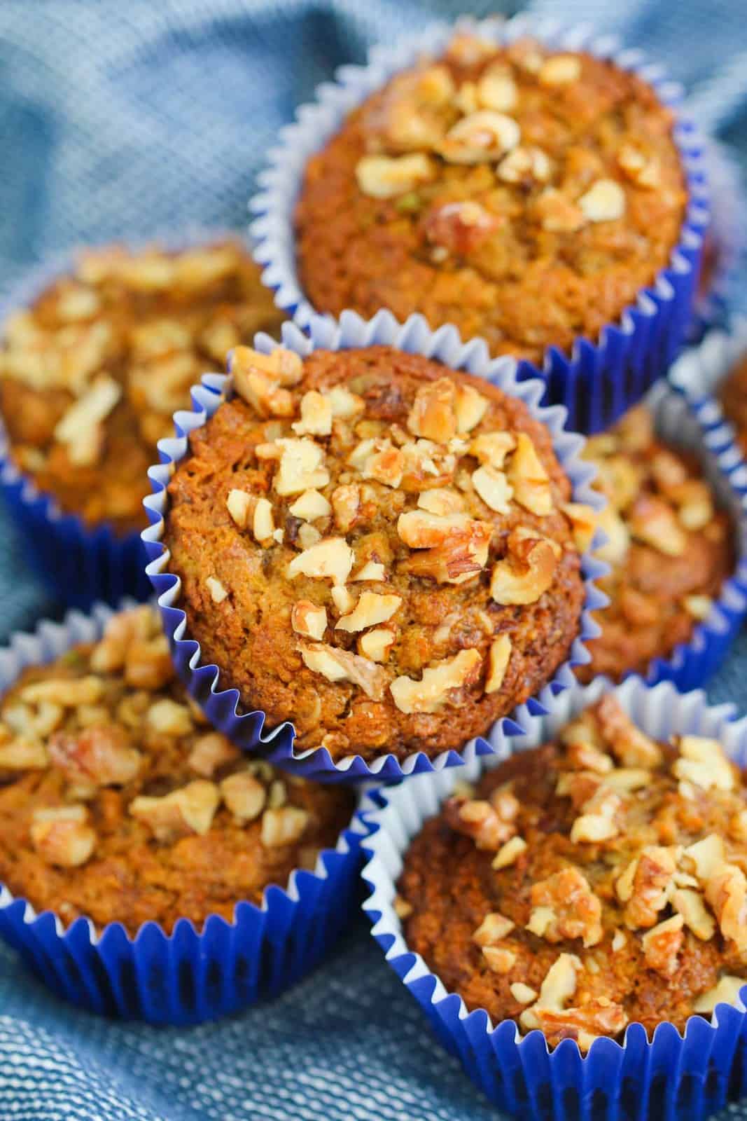 A pile of healthy muffins sprinkled with chopped walnuts on top.