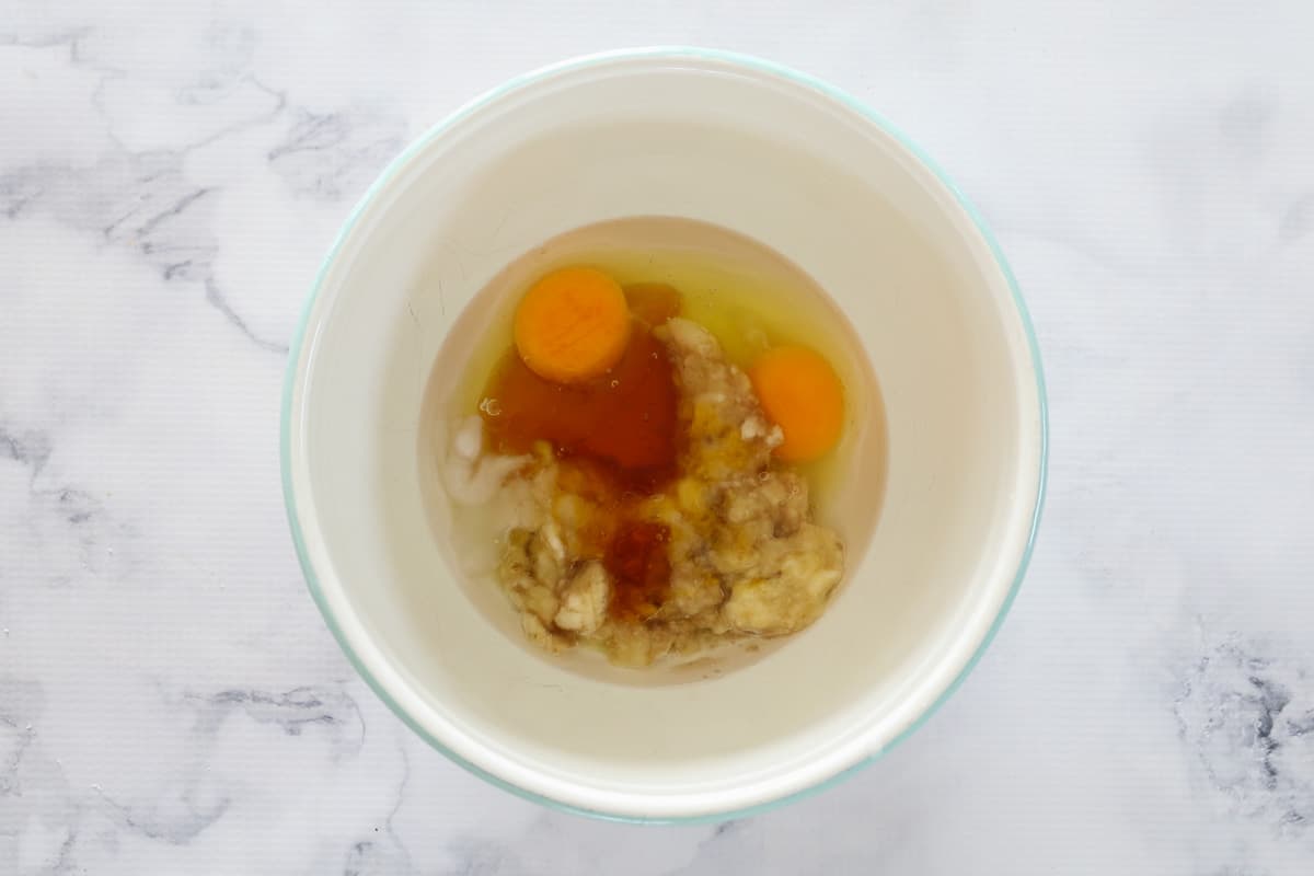 Eggs, mashed banana, honey and coconut oil in a mixing bowl.