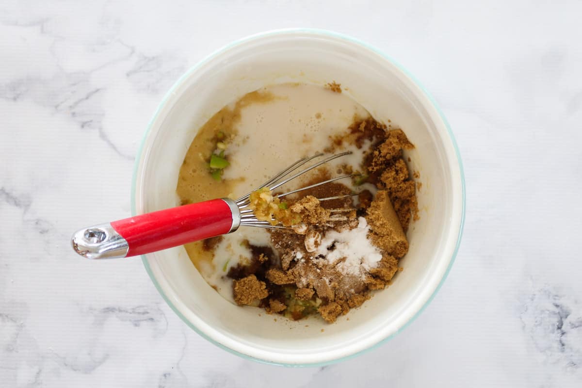 Apple, brown sugar, cinnamon and almond milk added to mixture in a bowl.