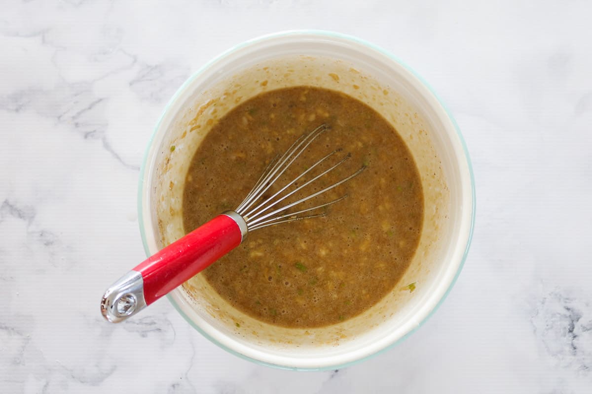 Carrot cake muffin mixture being whisked in a bowl.