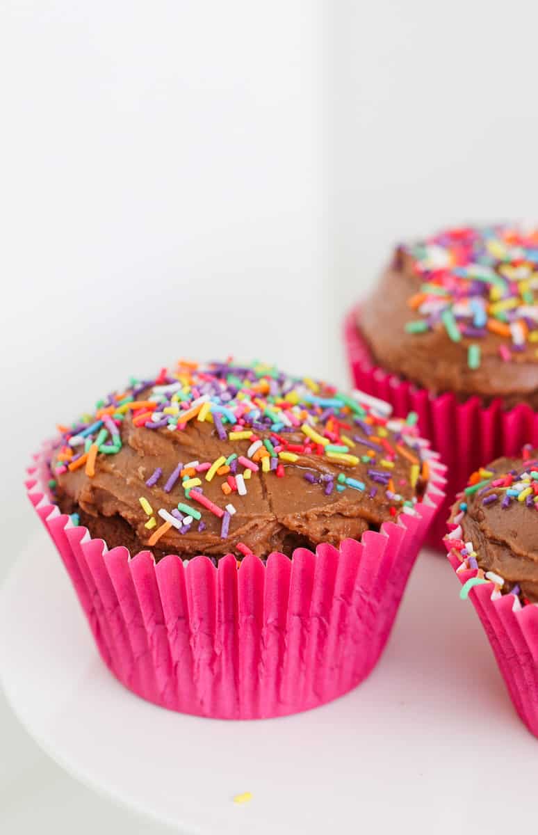 Pink cupcake cases with brown cupcakes and frosting.