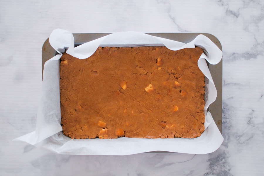 A chocolate no-bake slice with chunks of honeycomb in a baking tray.