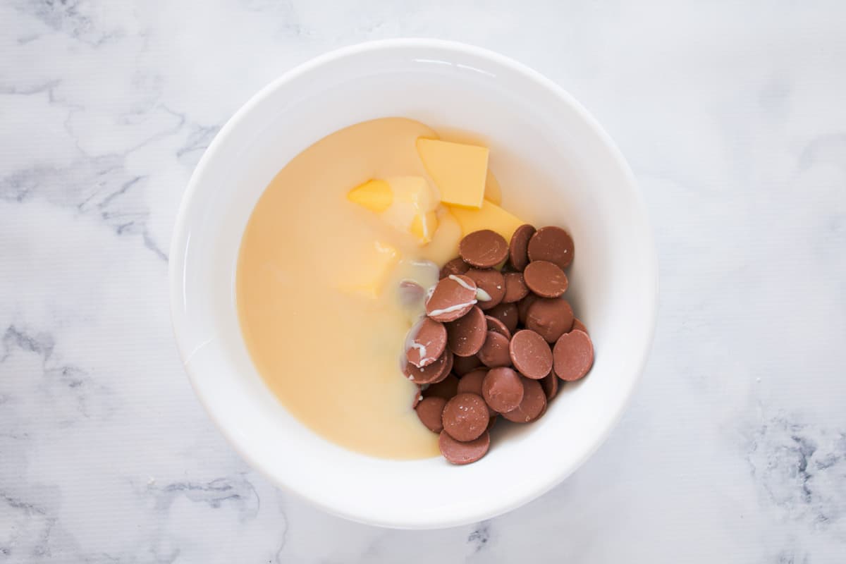 Butter, chocolate and sweetened condensed milk in a bowl.