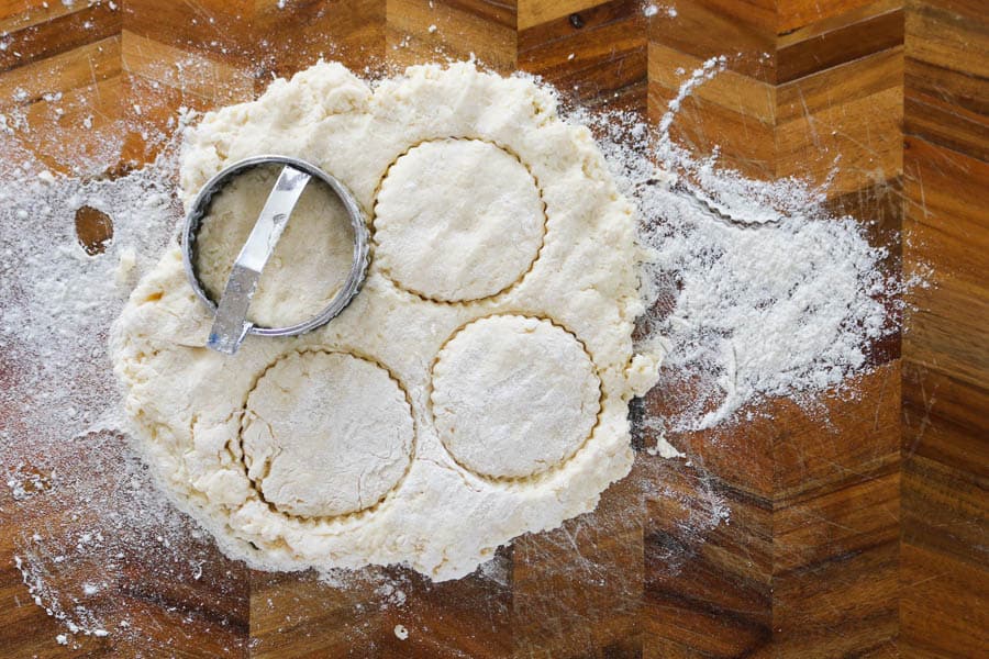 Round scones being cut out with a metal cutter.