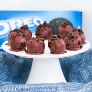 A cake tray of chocolate coated truffles, decorated with chocolate, in front of a packet of Oreo's