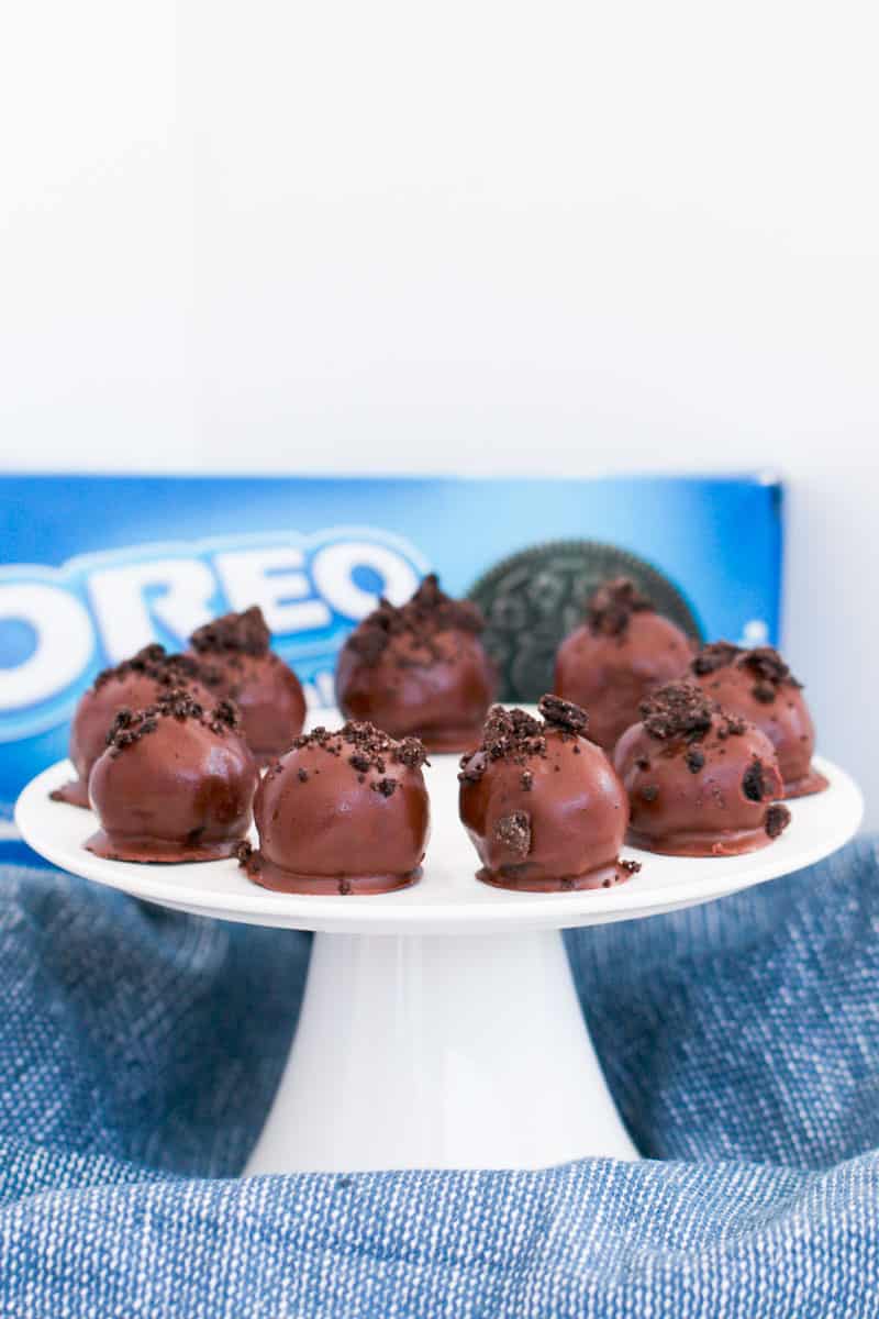 A plate of cream cheese balls coated in chocolate with a packet of Oreos in the background.