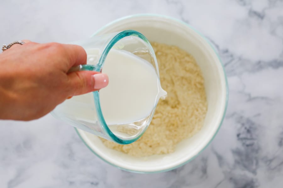 Milk being poured on top of butter and self-rising flour in a bowl.