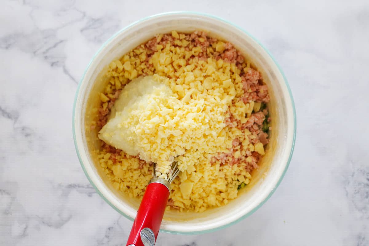 Chopped bacon, grated cheese and diced onion in a mixing bowl.