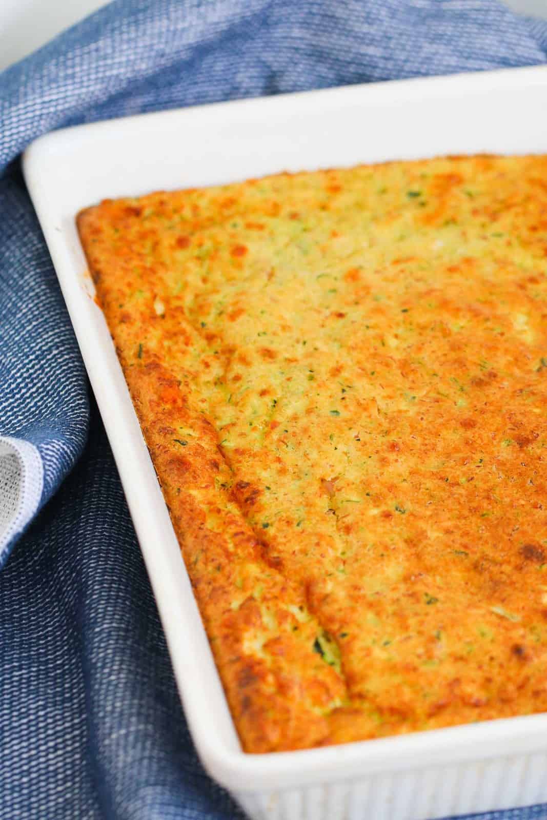 A whit baking dish filled with golden homemade zucchini slice.