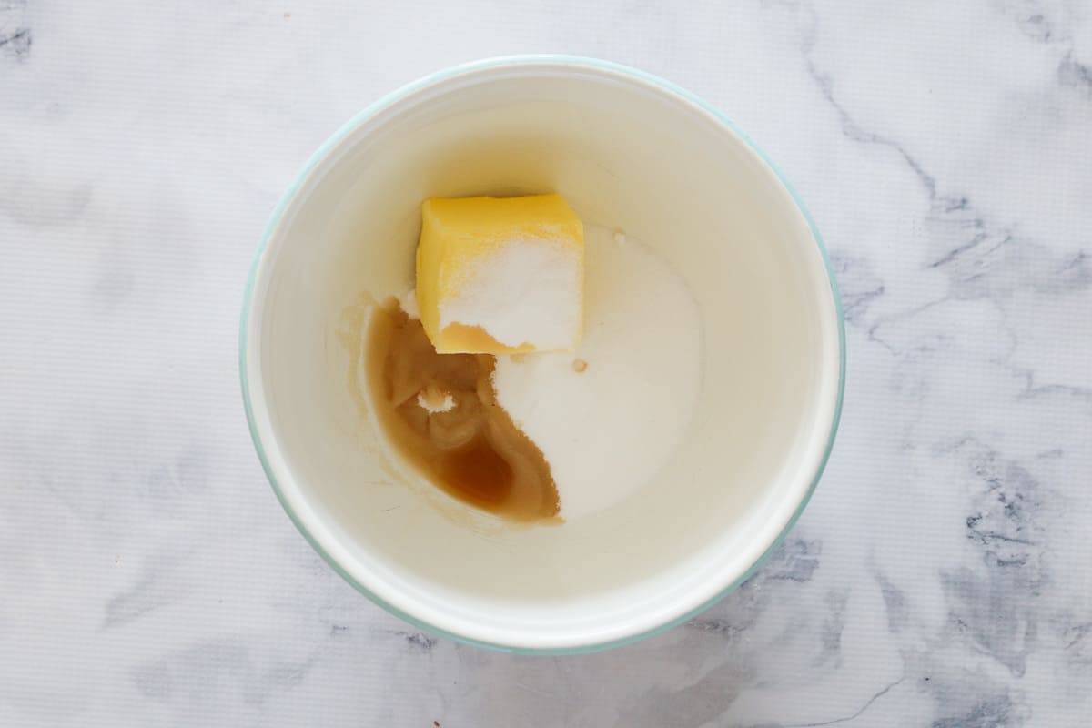 Butter, sugar and vanilla extract in a white bowl.
