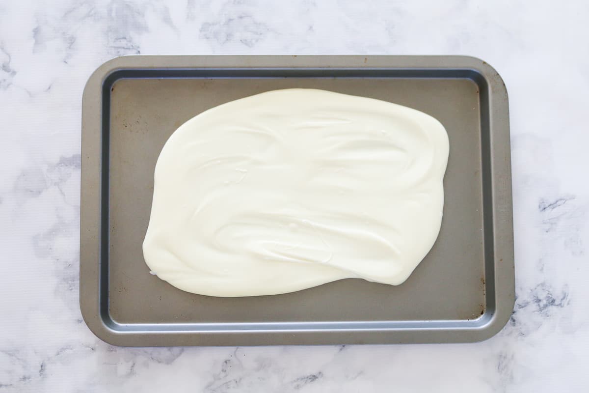 Melted white chocolate spread across a baking tray.