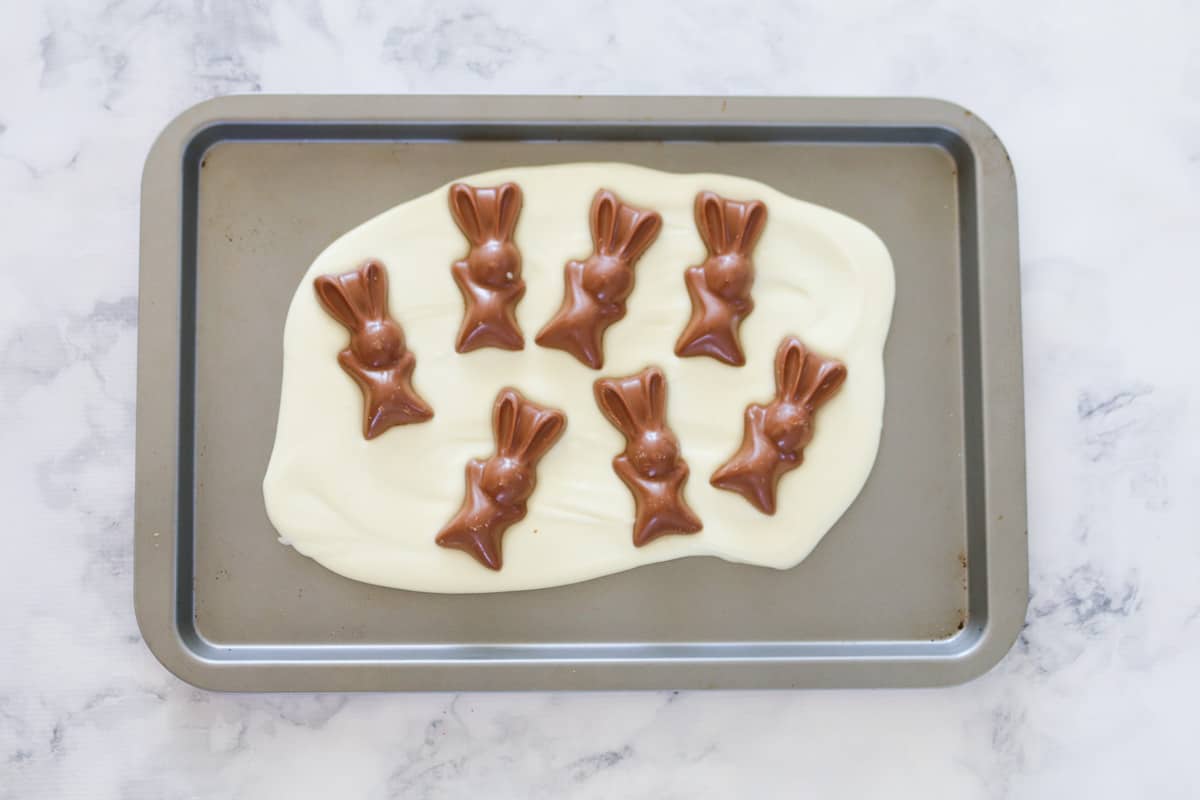 Malteser bunnies decorated on top of melted white chocolate.