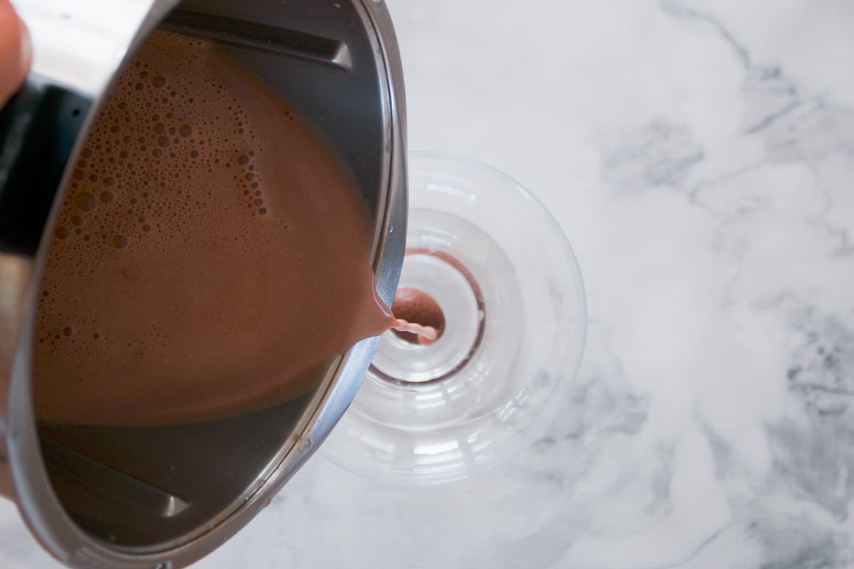 A chocolate cocktail being poured into a cocktail glass.