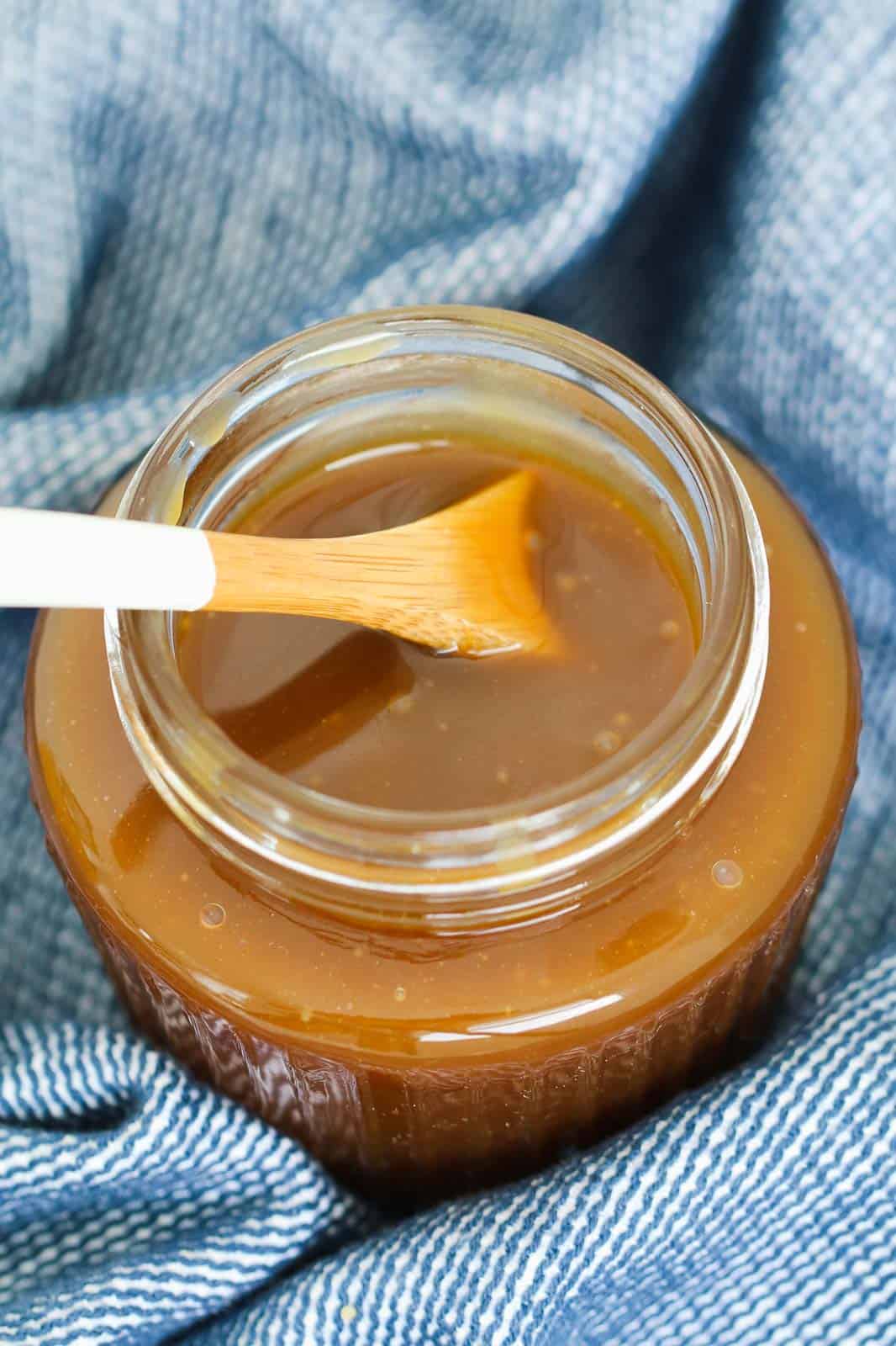 A spoon in a jar of homemade caramel.