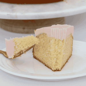 A forkful of butter cake topped with pink frosting.