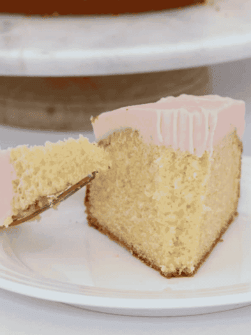 A forkful of butter cake topped with pink frosting.