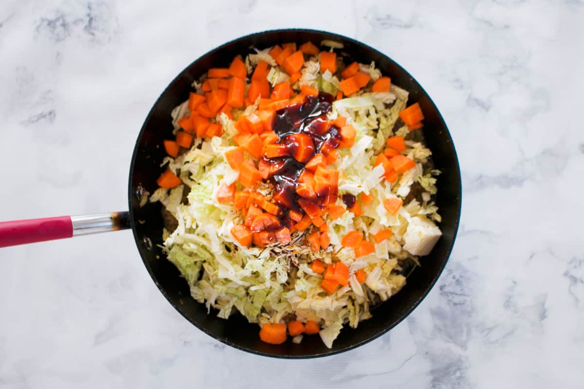 Cabbage, carrot, soy sauce and oyster sauce in a frying pan.