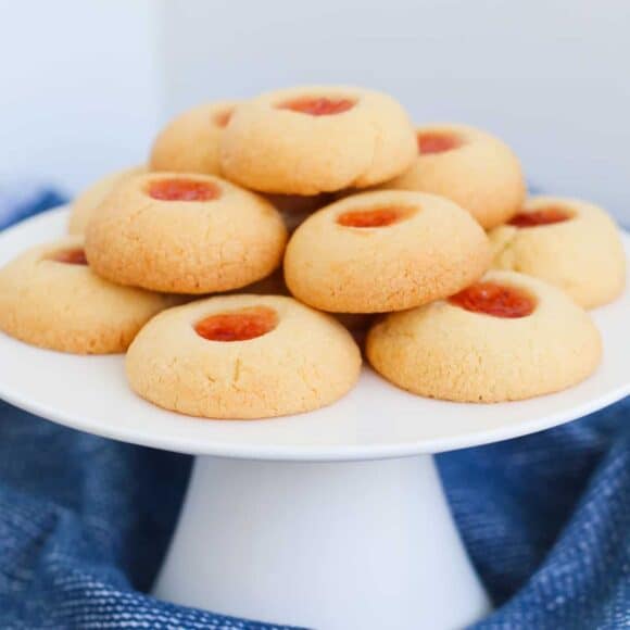 A plate of golden jam drop cookies with bright jam centres.