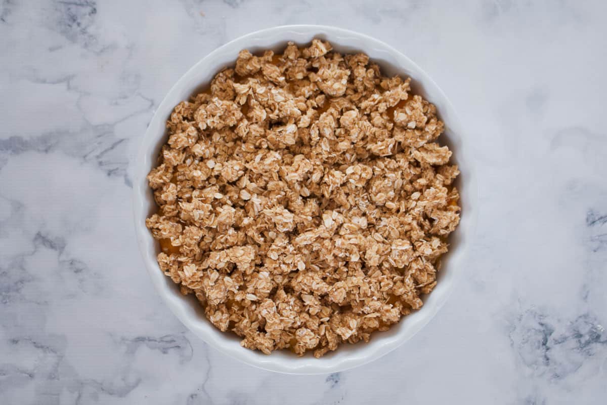 A dessert baking dish topped with brown sugar and rolled oat mixture.