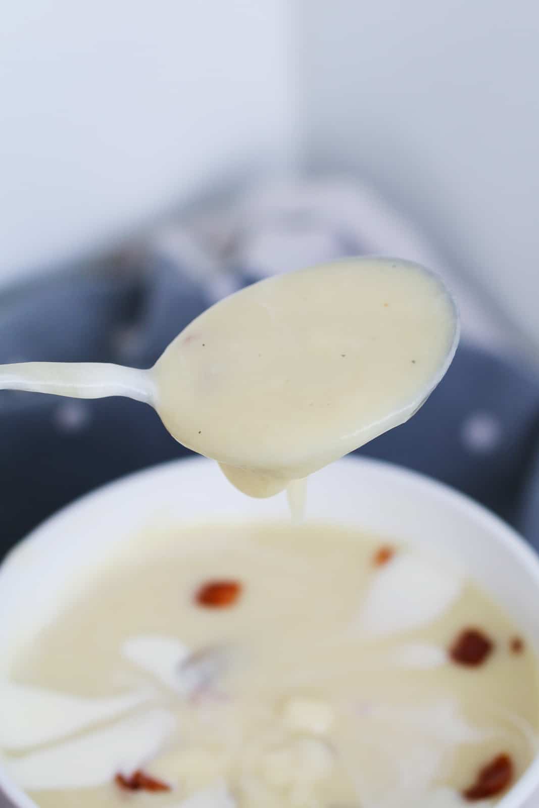 A soup spoon holding creamy vegetable soup.
