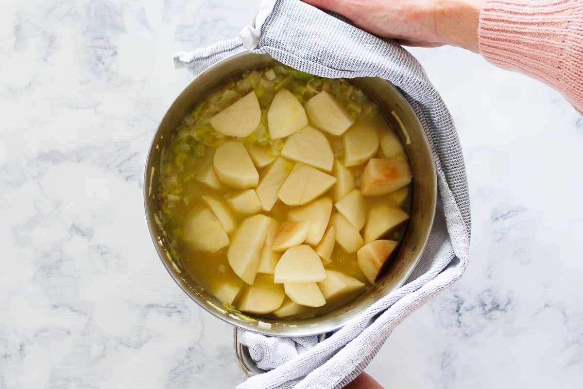 Diced potatoes in a saucepan filled with chicken stock.