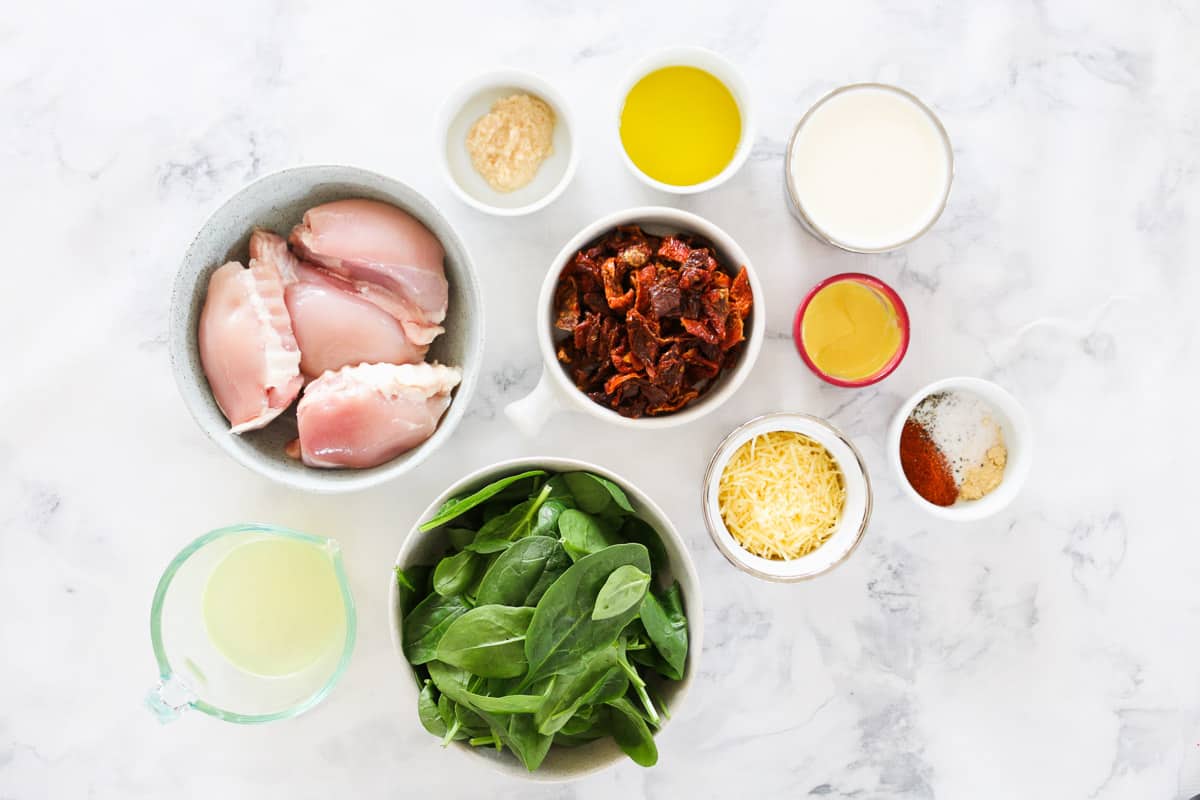 The ingredients for a creamy chicken dish with sun-dried tomatoes and spinach.