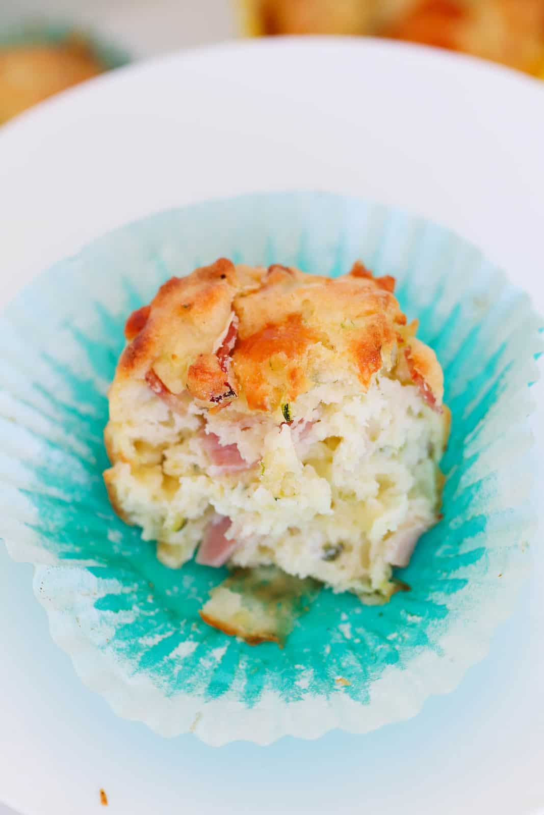 A fluffy zucchini and ham muffin broken in half.