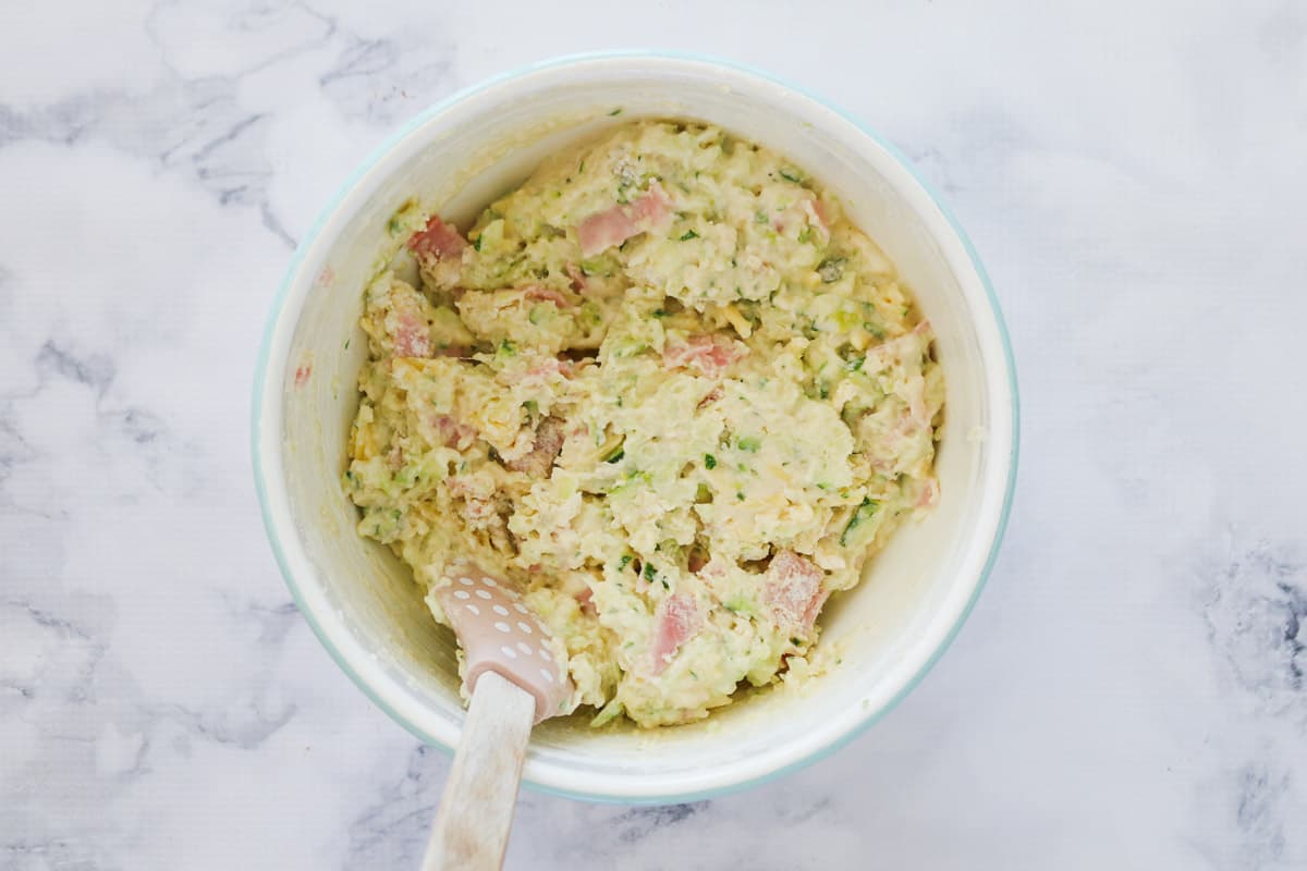 Chunks of ham and zucchini in a bowl of muffin mixture.